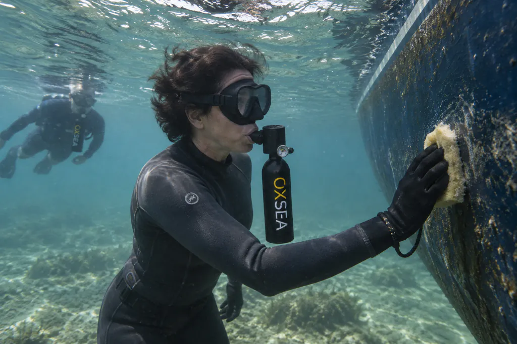 A boat owner cleans the hull underwater, breathing from an OXSEA OX500 tank.